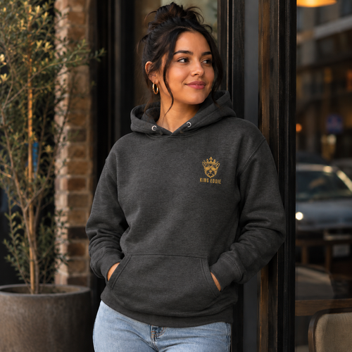 Woman wearing charcoal King Eddie Heritage Hoodie with gold crest logo outside a café