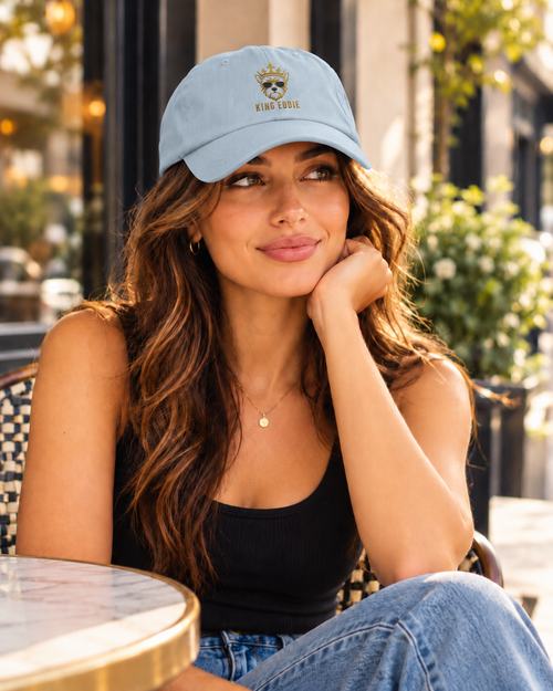 Woman wearing light blue King Eddie signature crest dad hat at an outdoor café